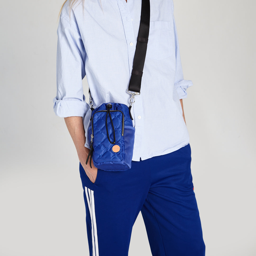 shortyLOVE bea sling bag in electric blue; on model in blue top against grey background.
