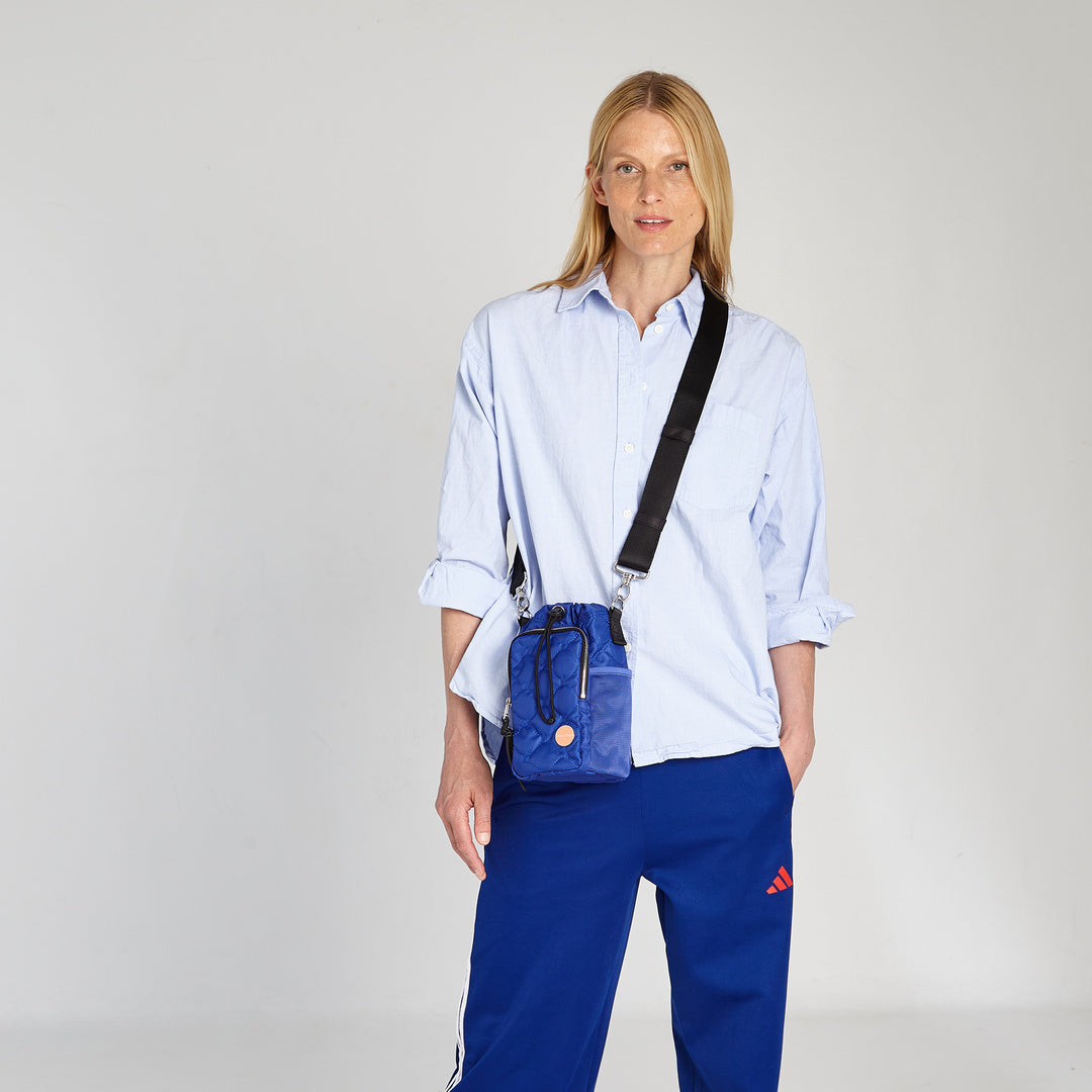shortyLOVE bea sling bag in electric blue; on model in blue top against grey background.