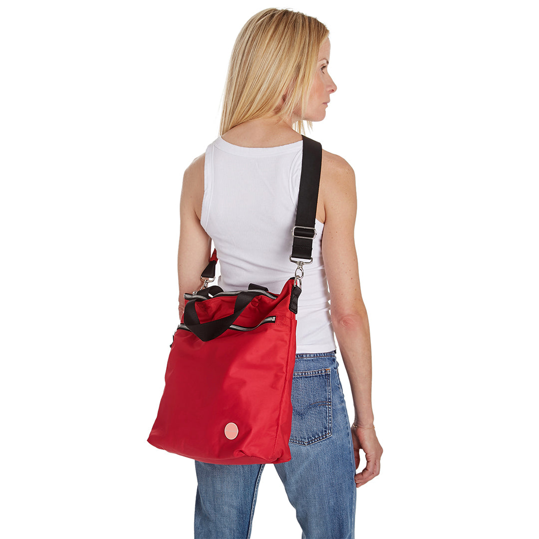 shortyLOVE wonder large crossbody/messenger bag in red; on model in white t-shirt and jeans against white background.