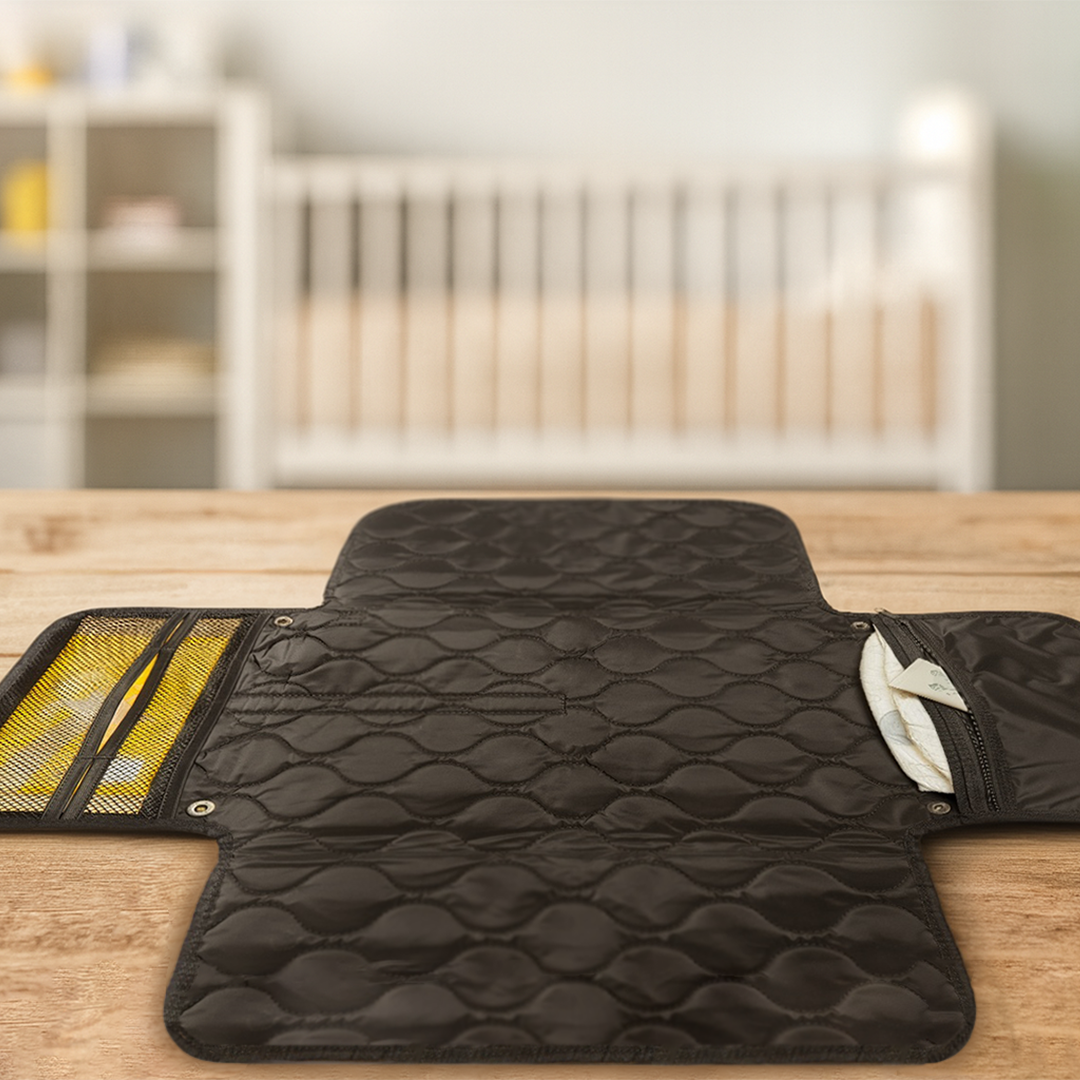 Black quilted diaper changing pad on a wooden surface with a blurred background
