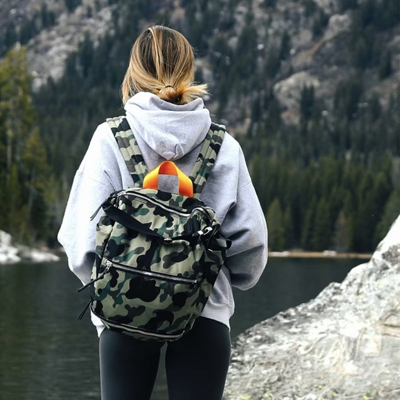 Person with a camouflage backpack and colorful duck on a mountain trail