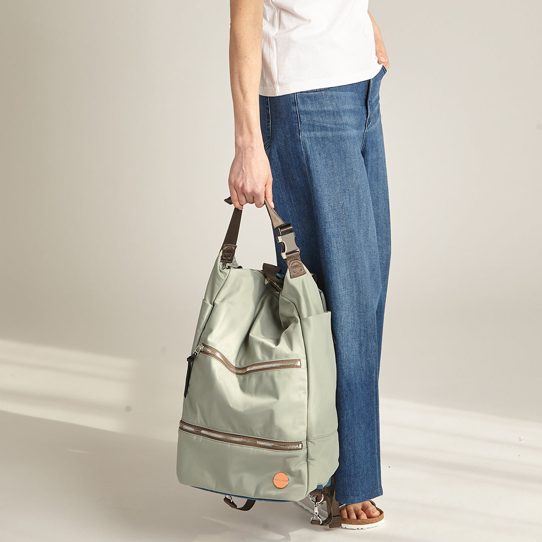woman hand holding a slate/teal boxer backpack against a plain background.