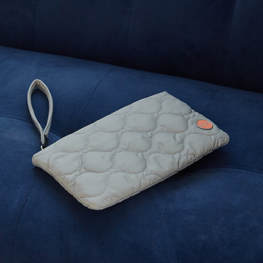 Quilted cleo clutch bag in grey on a blue couch