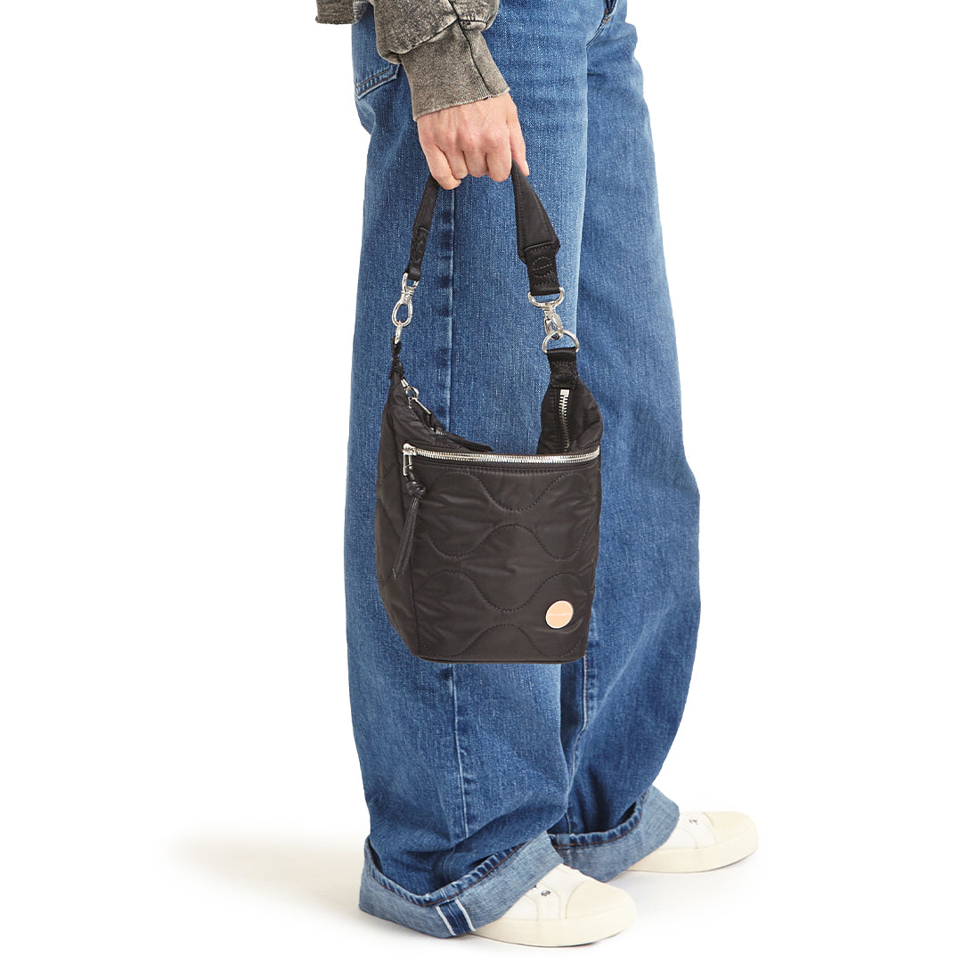black marcel quilted crossbody  handheld against a white background