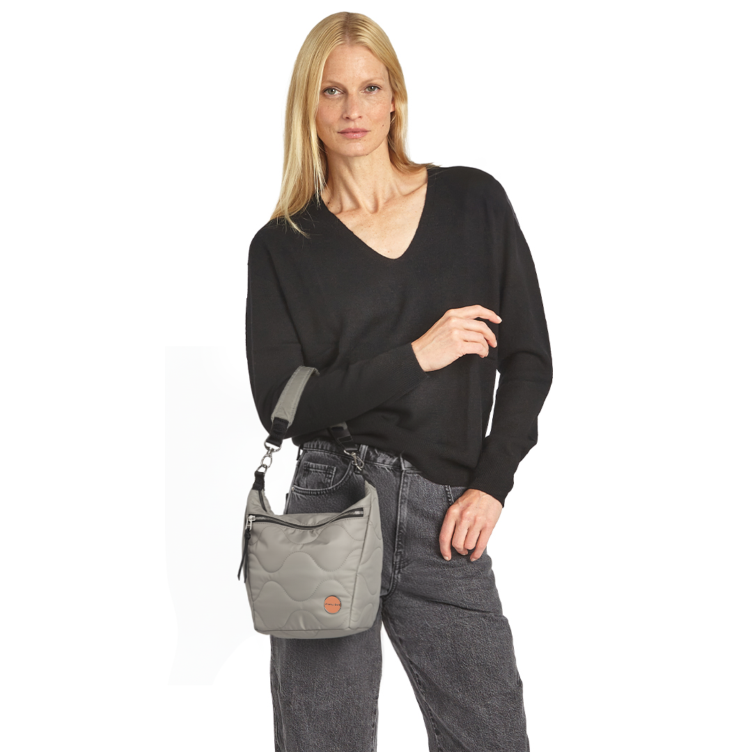 Woman holding a gray marcel quilted crossbody  handbag against a white background