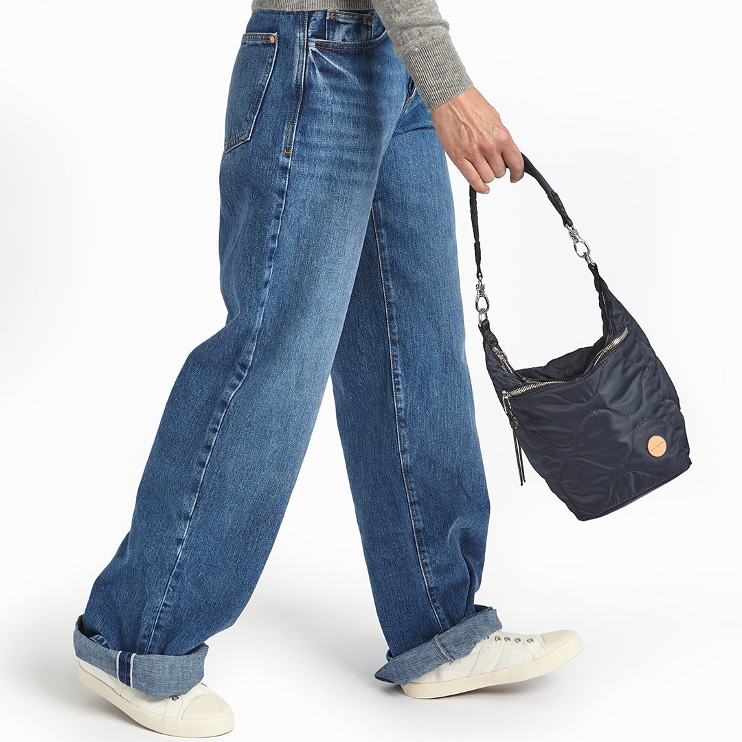 midnight blue marcel quilted crossbody  handheld against a white background