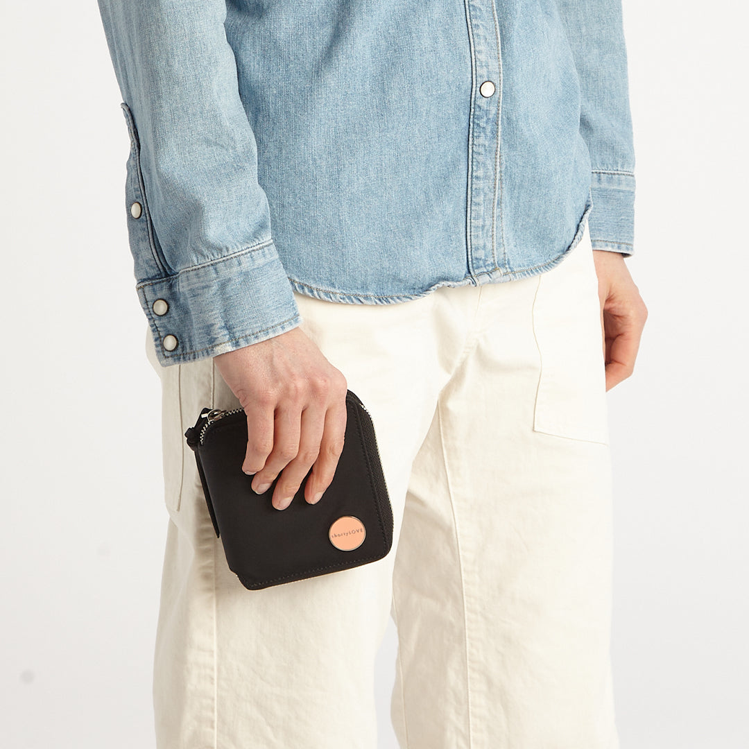 Person holding a black merchant wallet with a visible brand logo against a white background