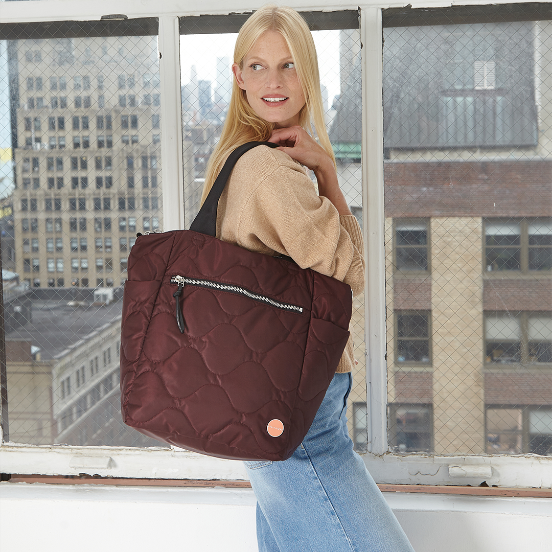 Woman holding a bordeaux quilted ranger tote bag in an urban setting