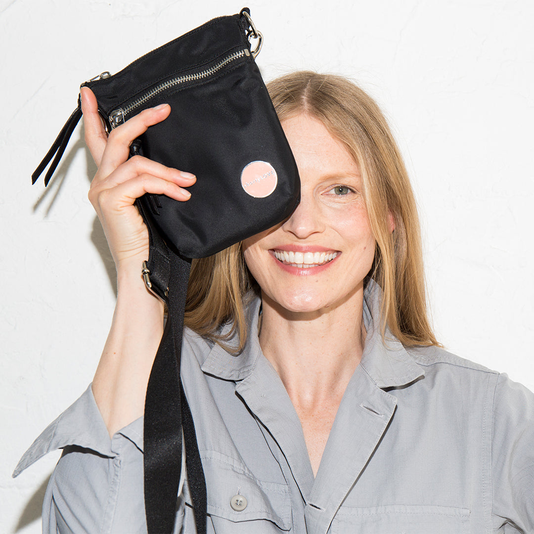 Woman holding a black shorthand crossbody bag against a white background