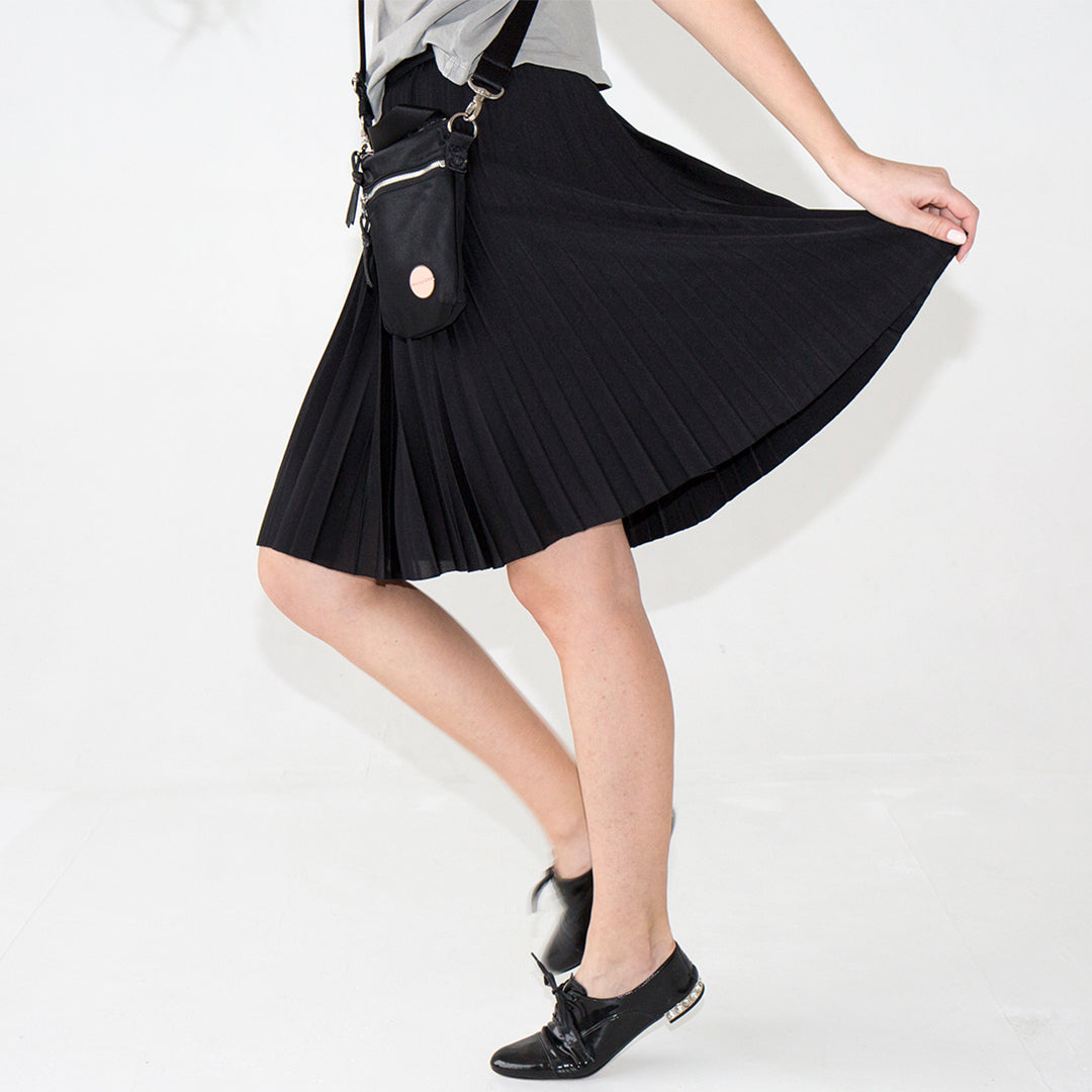 Person wearing a small black shorthand crossbody bag against a white background