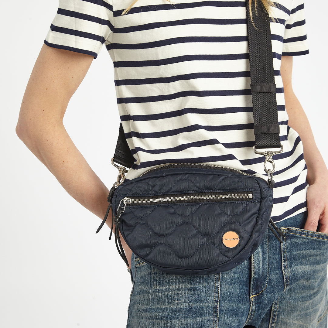 Woman in striped shirt wearing a midnight blue small cruiser quilted crossbody bag 
