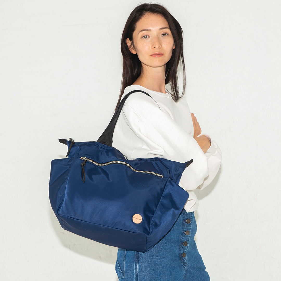 Woman carrying a navy blue tillie tote bag on a white background