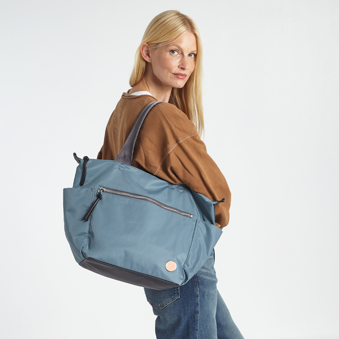 Woman carrying a steel blue tillie tote bag on a white background