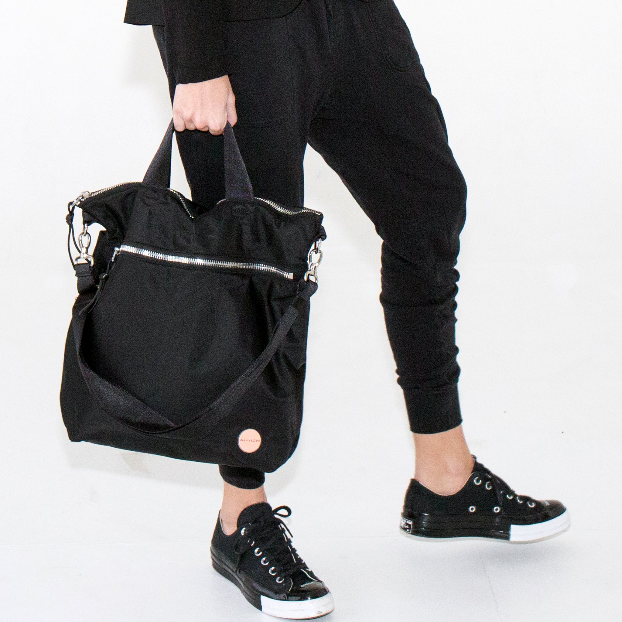 Person hand holding a black wonder crossbody bag by the handles against a white background.