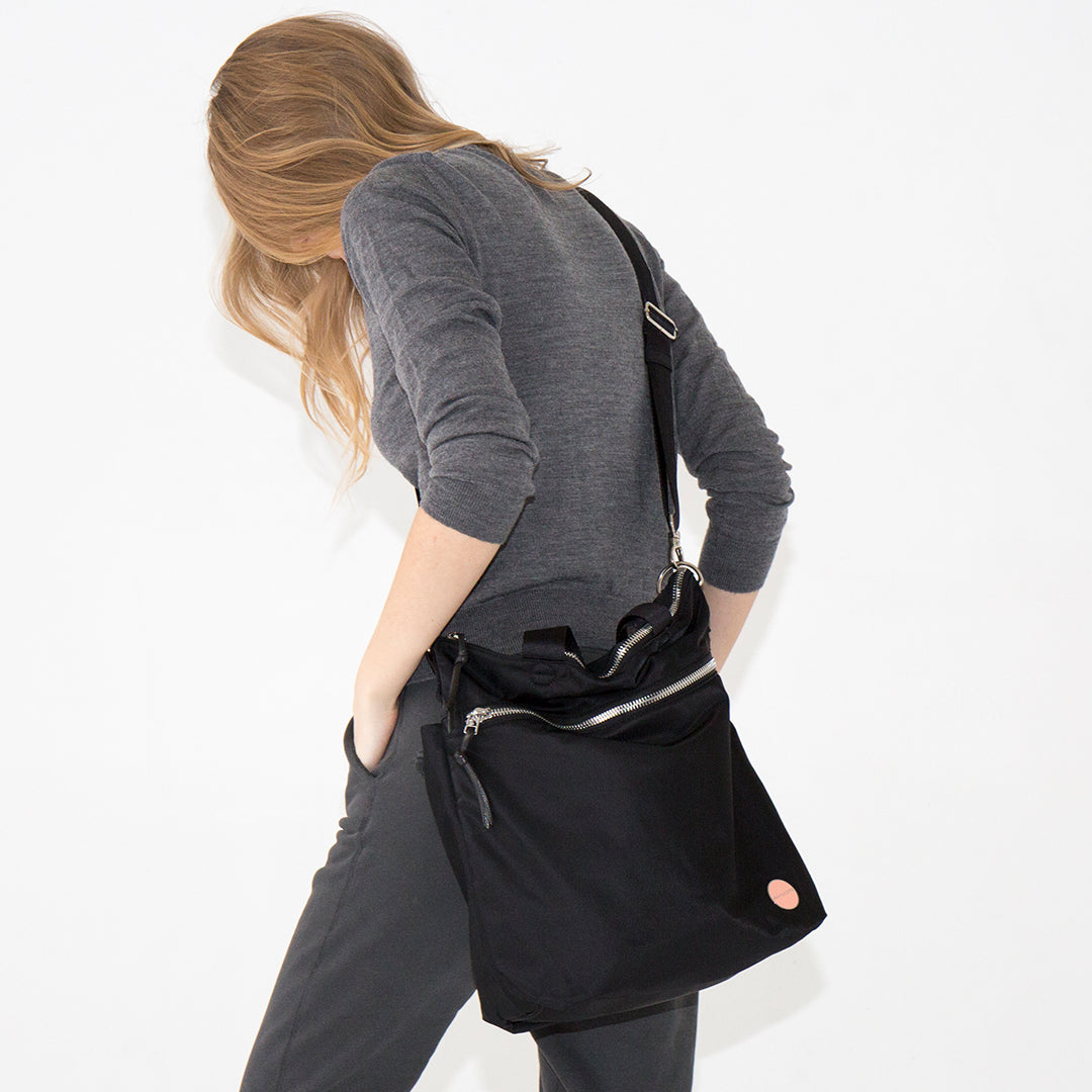 Person wearing a black wonder crossbody bag on a white background