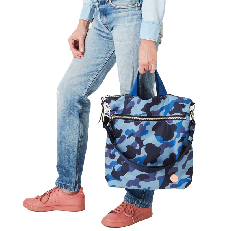 shortyLOVE wonder large crossbody/messenger bag in blue camo; in hand of model in blue top and jeans against white background.