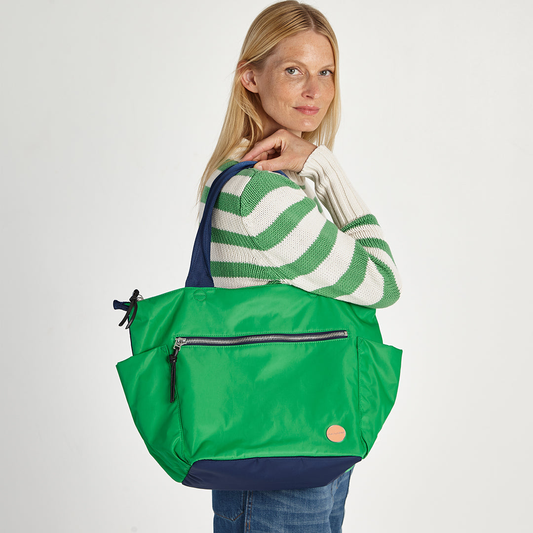 shortyLOVE tillie tote bag in grass green/navy; on model in green striped sweater against white background.