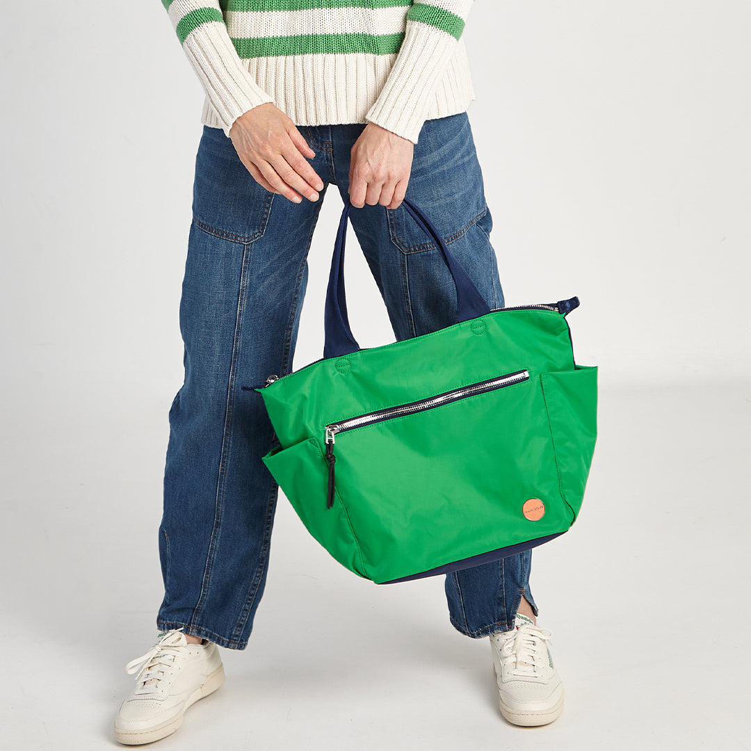 shortyLOVE tillie tote bag in grass green/navy; hand held by model in green striped sweater against white background.