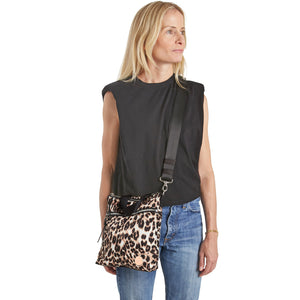 shortyLOVE amuse medium sized crossbody bag in leopard; on model in black top and jeans against white background.
