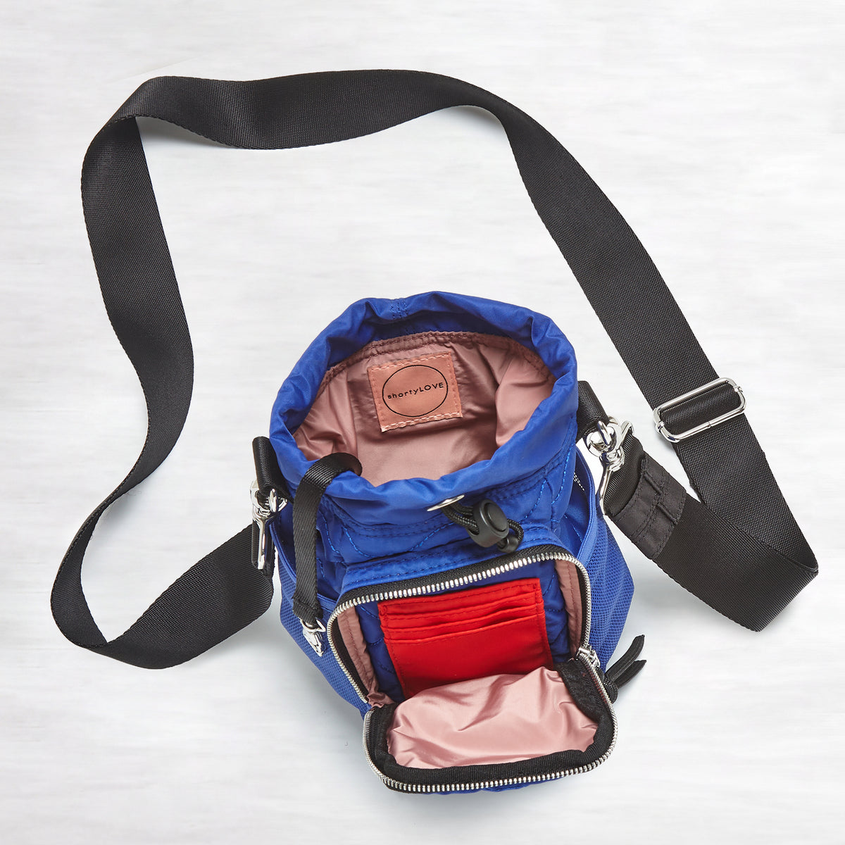 shortyLOVE bea sling bag in electric blue; top-down view showing interior blush lining against grey background.