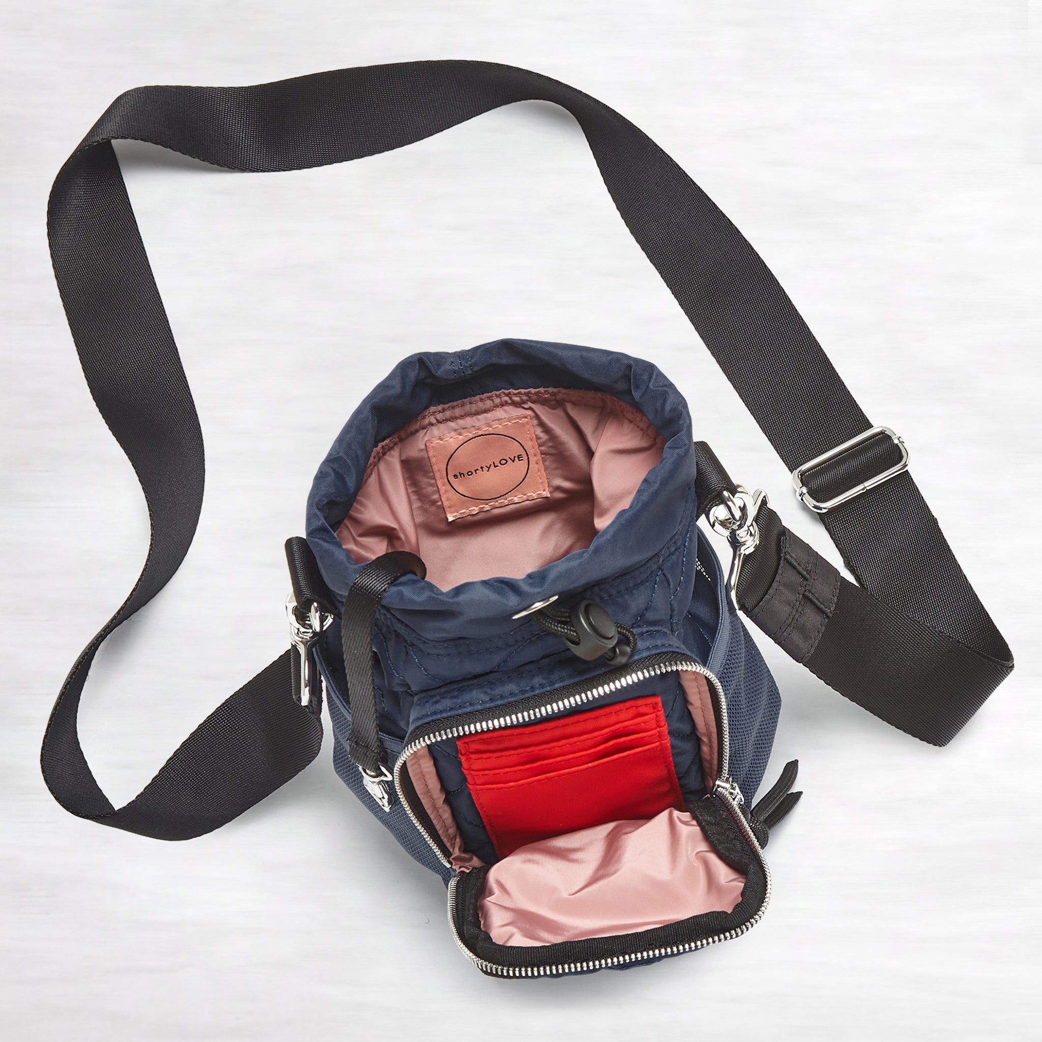 shortyLOVE bea sling bag in midnight; top-down view showing interior blush lining against grey background.