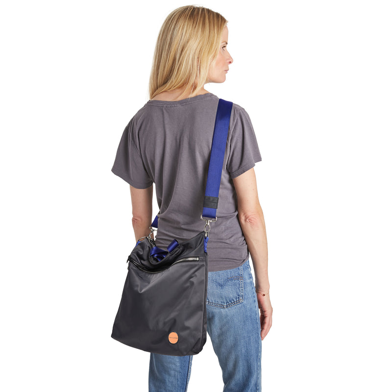 shortyLOVE wonder large crossbody/messenger bag in charcoal; on model in grey t-shirt and jeans against white background.