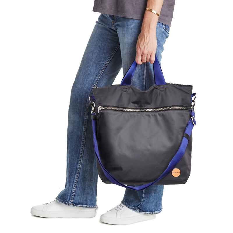 shortyLOVE wonder large crossbody/messenger bag in charcoal; hand held by model in jeans against white background.