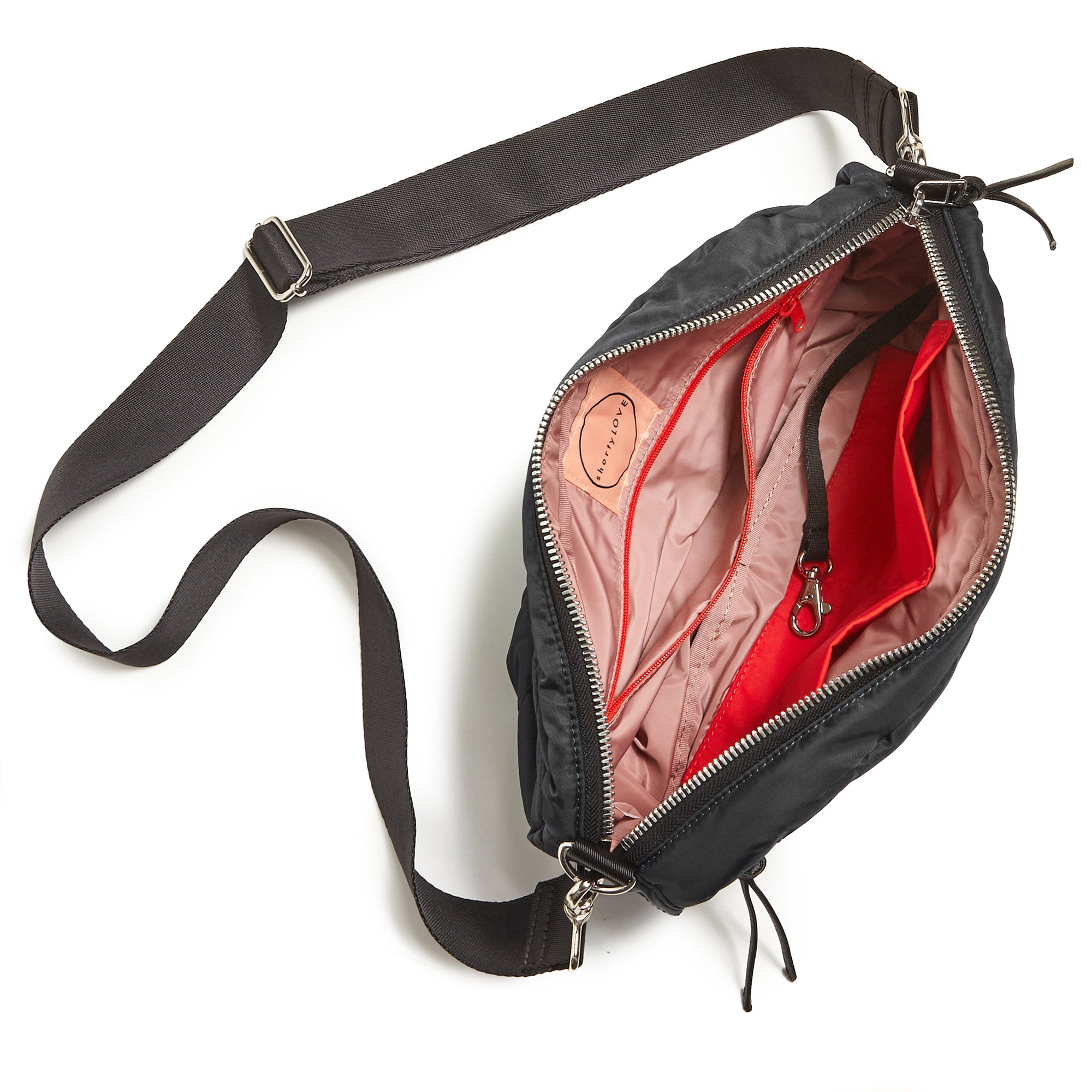 shortyLOVE cruiser medium crossbody bag in black; top-down view showing interior blush lining against white background.