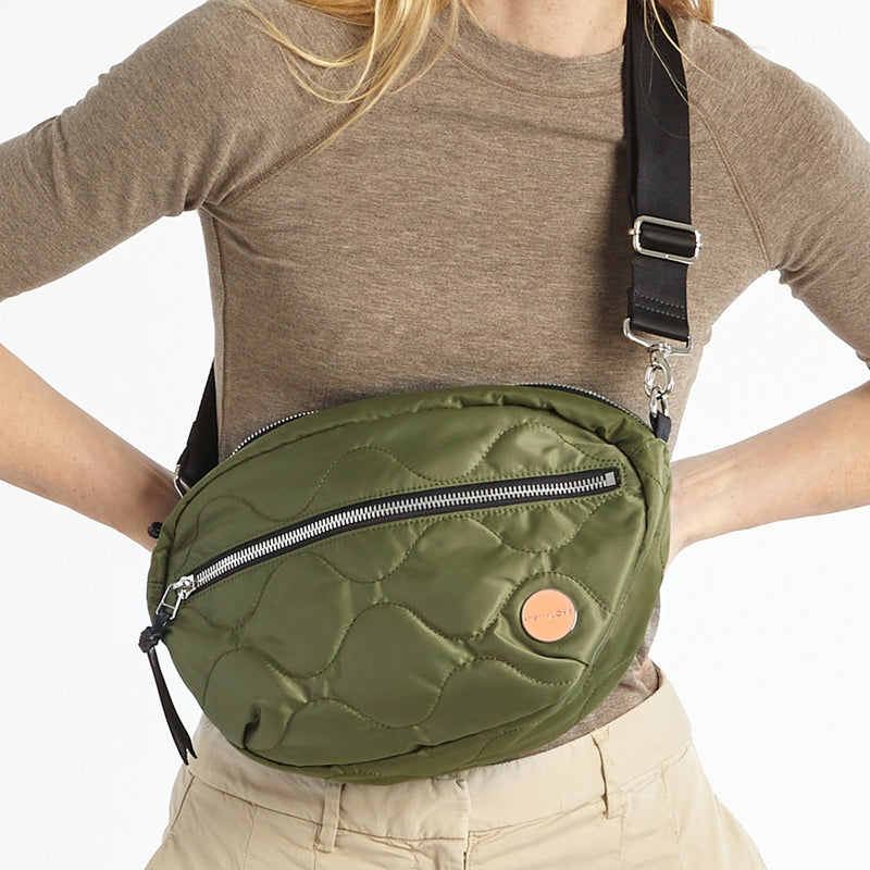 shortyLOVE cruiser medium crossbody bag in sage; on model in a tan top and pants against white background.