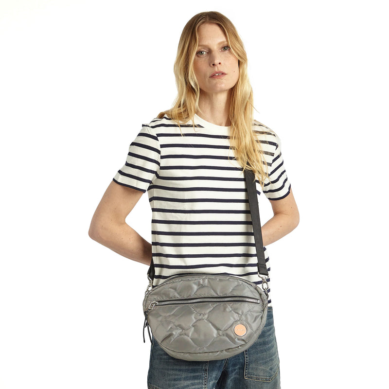shortyLOVE cruiser medium crossbody bag in milky grey; on model in striped t-shirt and jeans against white background.