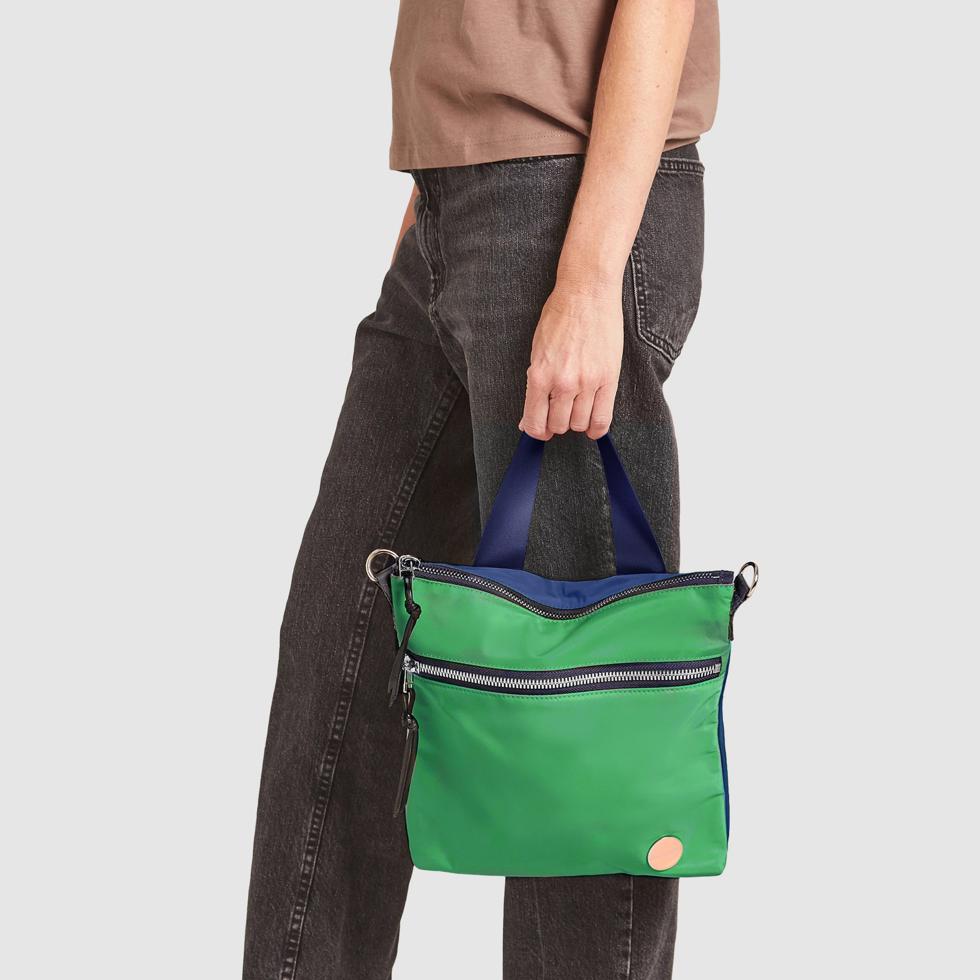 shortyLOVE amuse medium sized crossbody bag in grass green/navy; hand held by model.