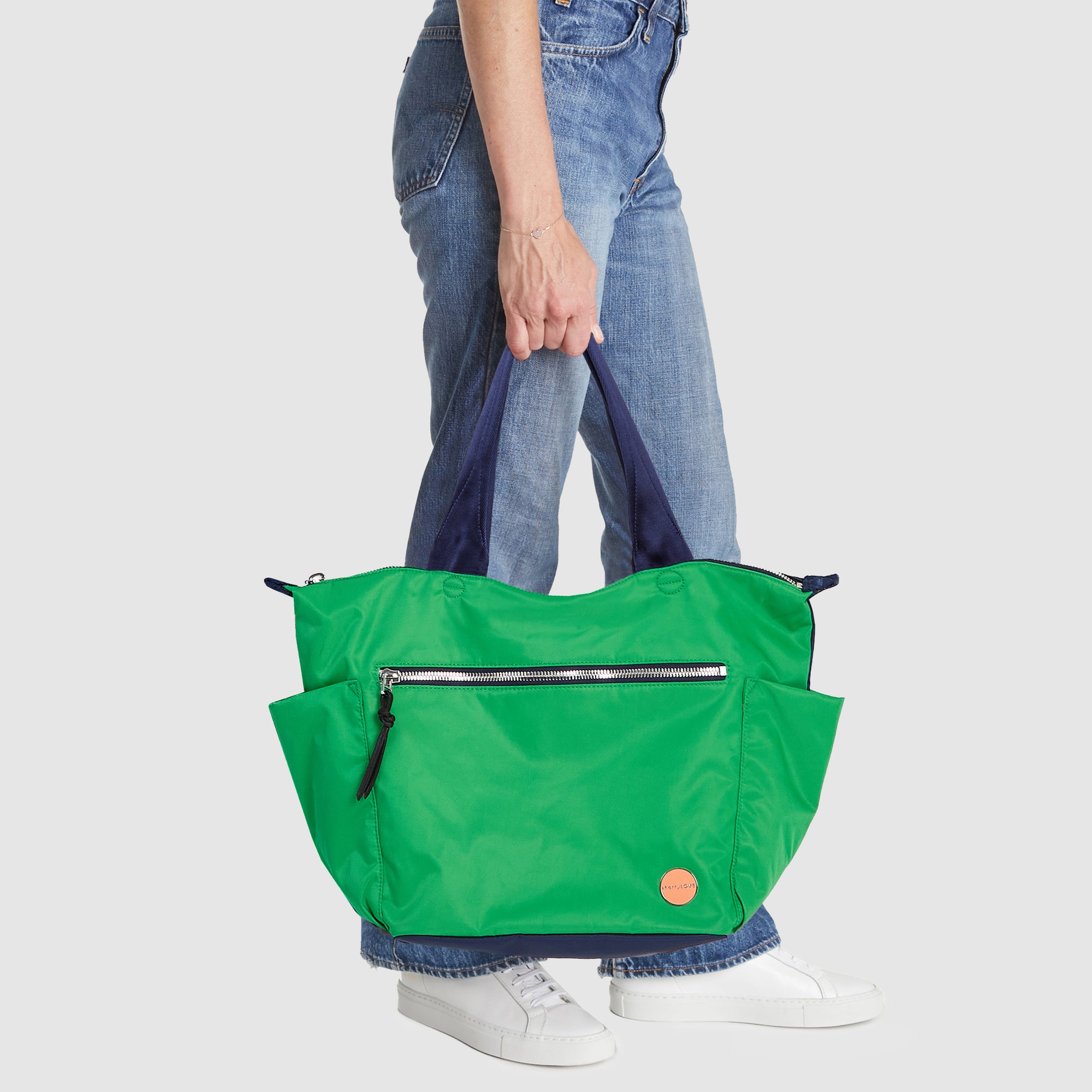 shortyLOVE tillie tote bag in grass green/navy; hand held model in jeans against white background.