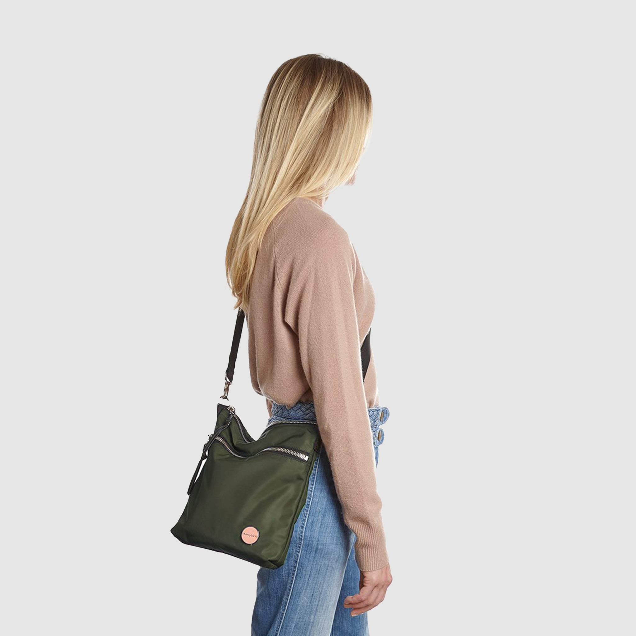shortyLOVE amuse medium sized crossbody bag in army green; on model in tan v-neck long sleeve sweater and jeans against white background.