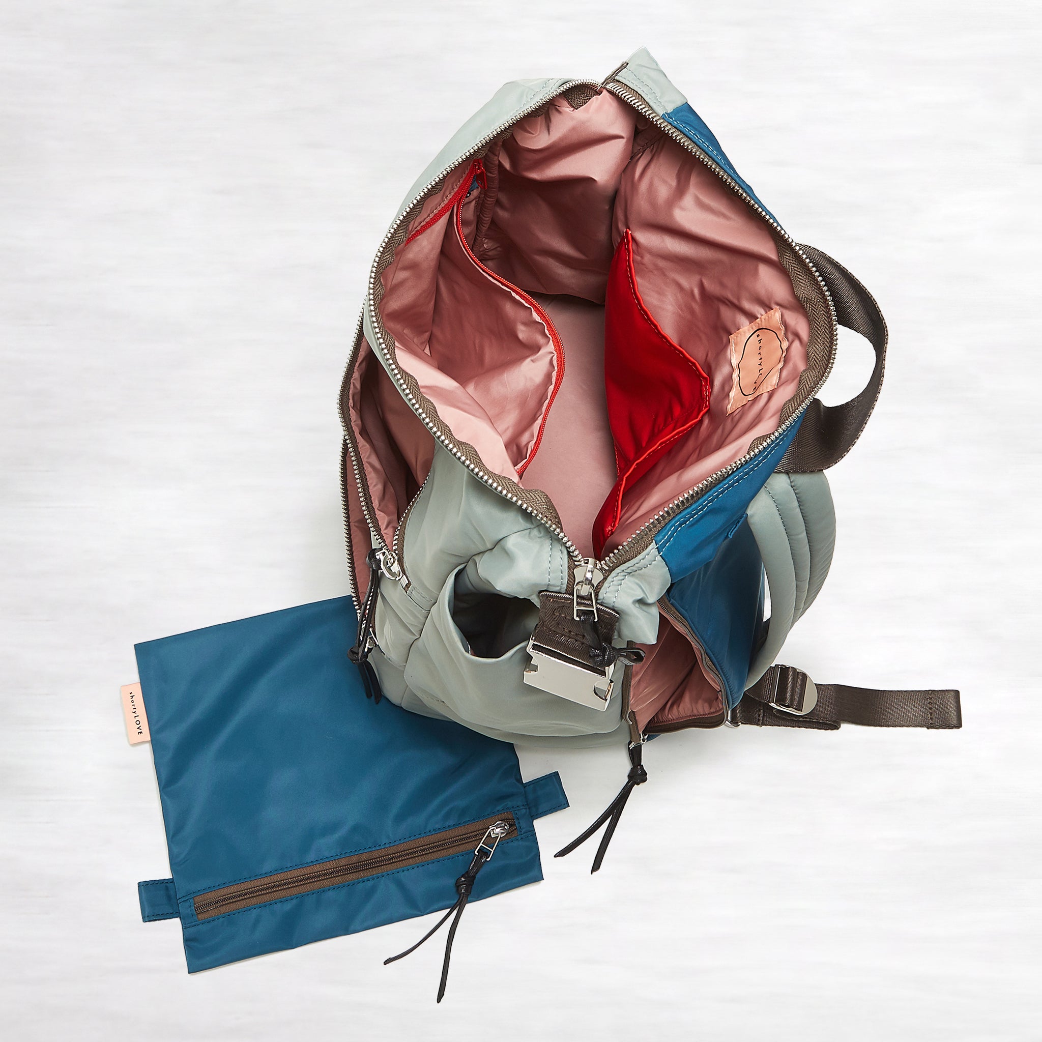 shortyLOVE boxer backpack in slate/teal; top-down view showing interior pink lining against white background.