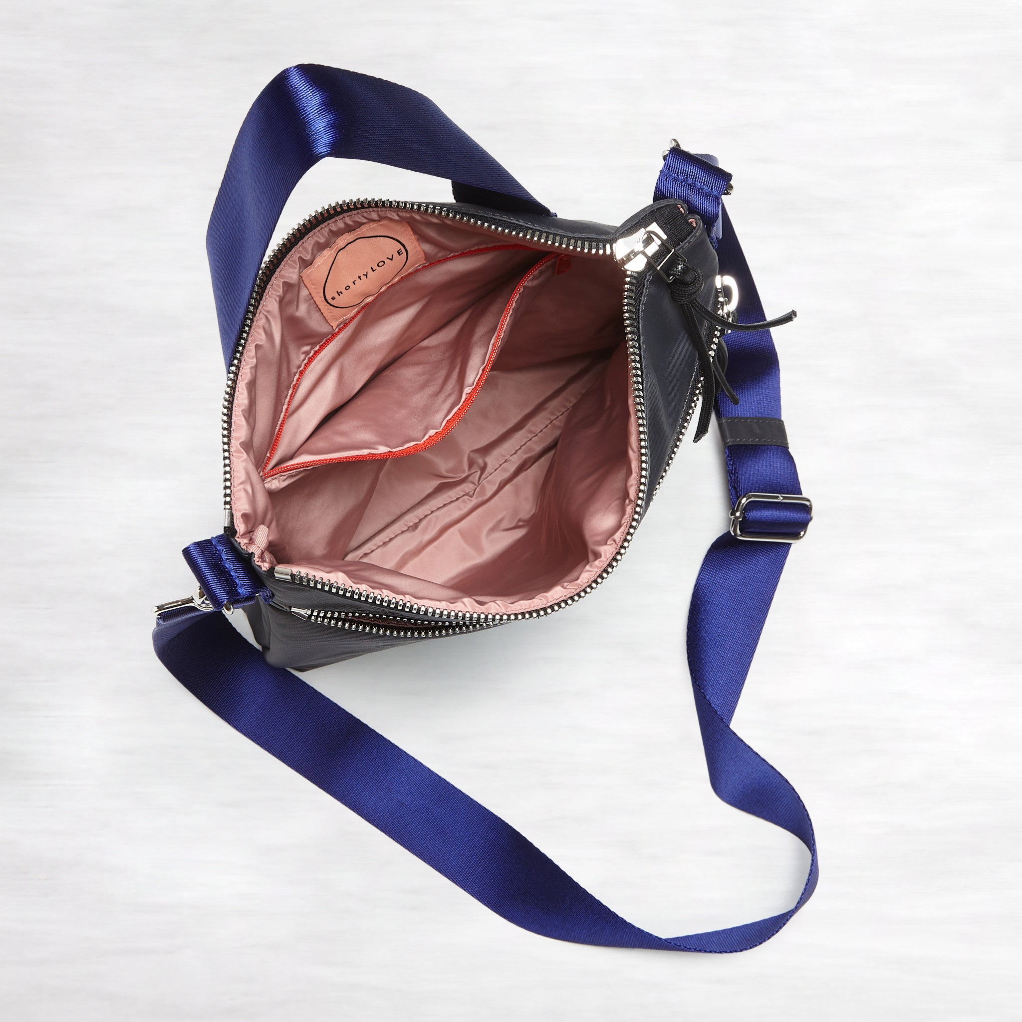 shortyLOVE amuse medium sized crossbody bag in charcoal; top-down view showing interior blush/red lining against white background.