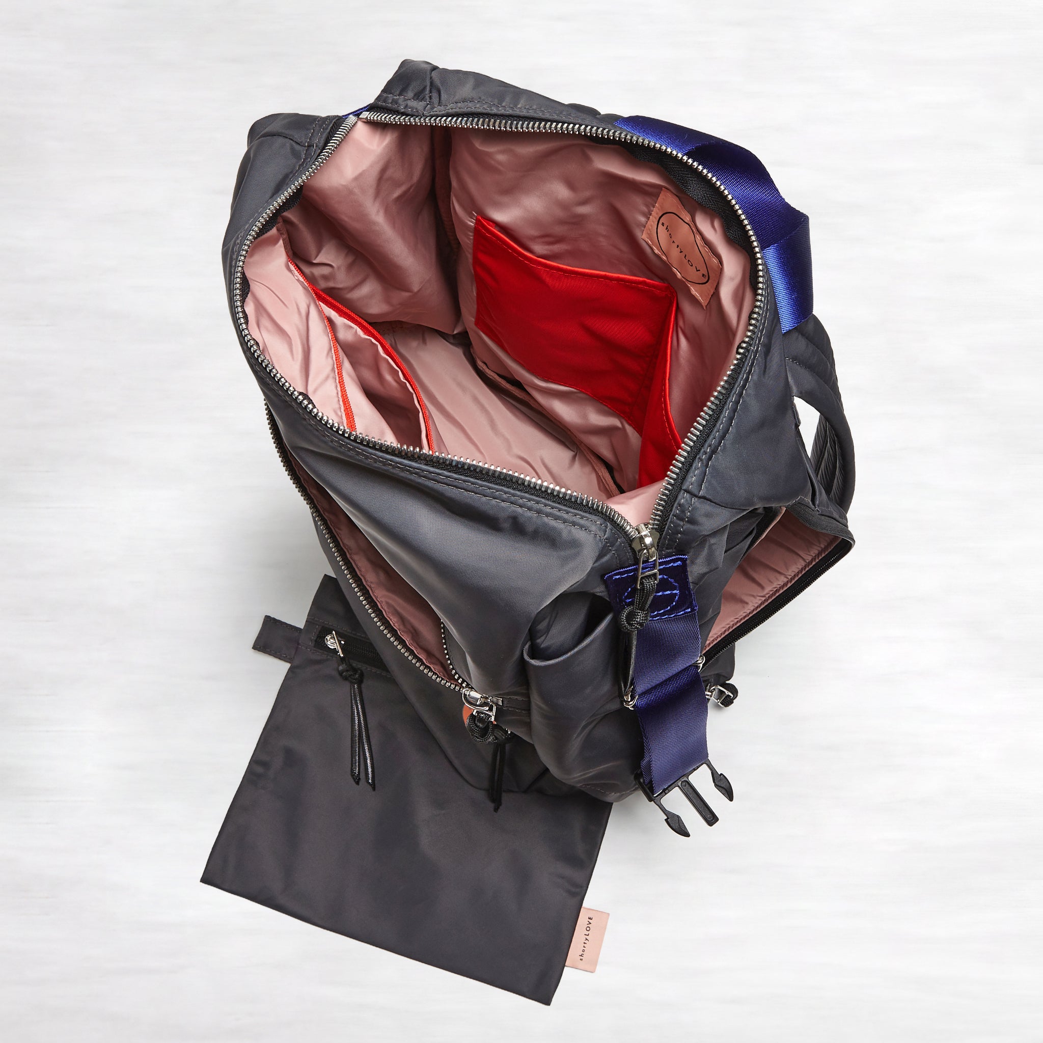 shortyLOVE boxer backpack in charcoal; top-down view showing interior blush/red lining against white background.