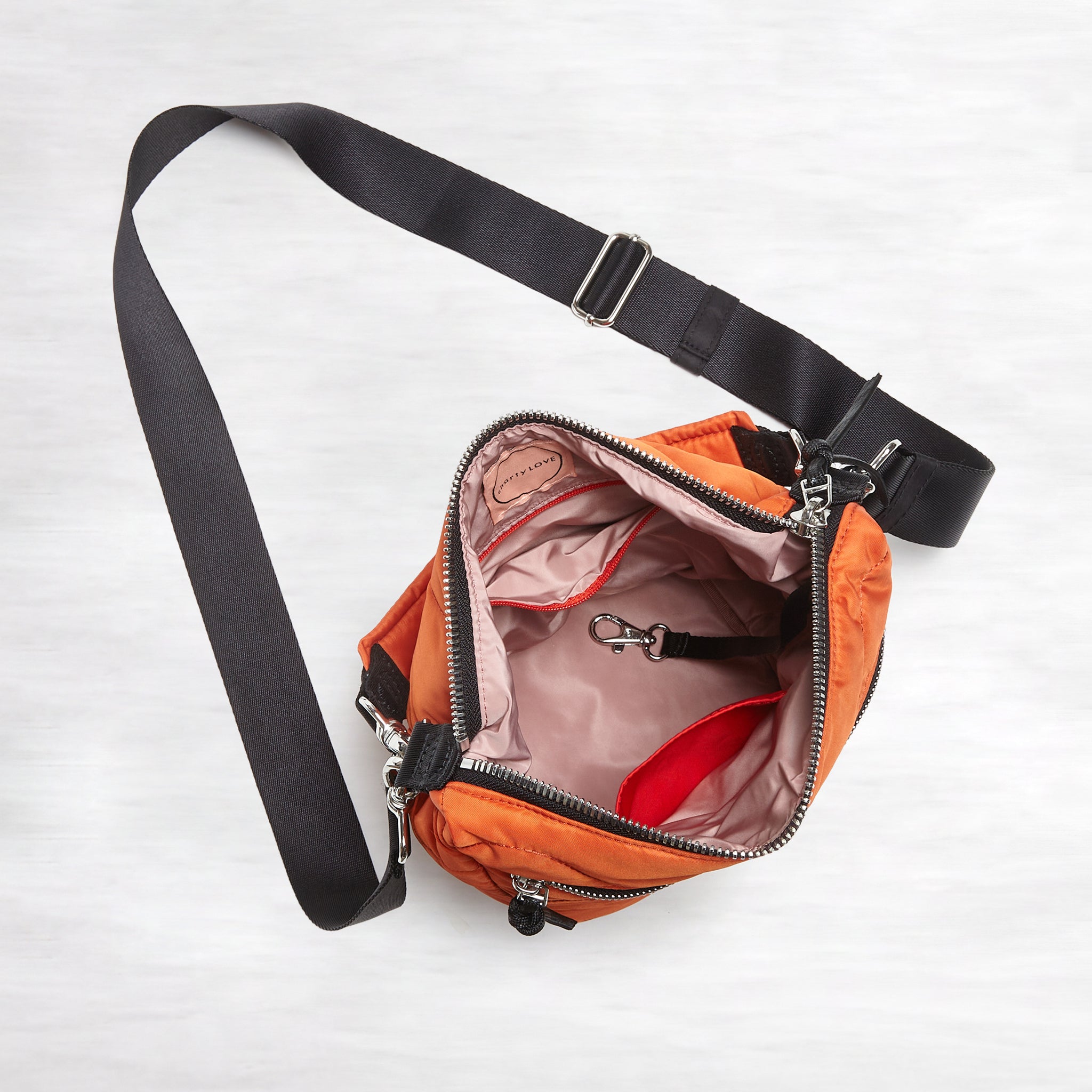 shortyLOVE marcel crossbody bucket bag in orange; top-down view showing interior blush lining against white background.