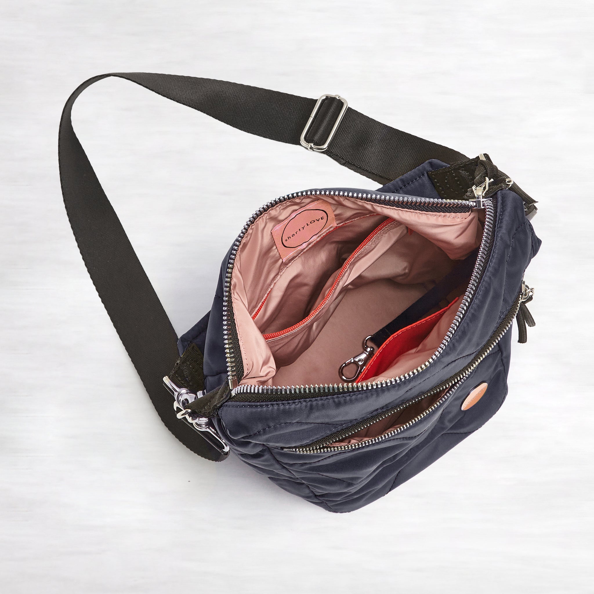 shortyLOVE marcel crossbody bucket bag in midnight; top-down view showing interior blush lining against white background.