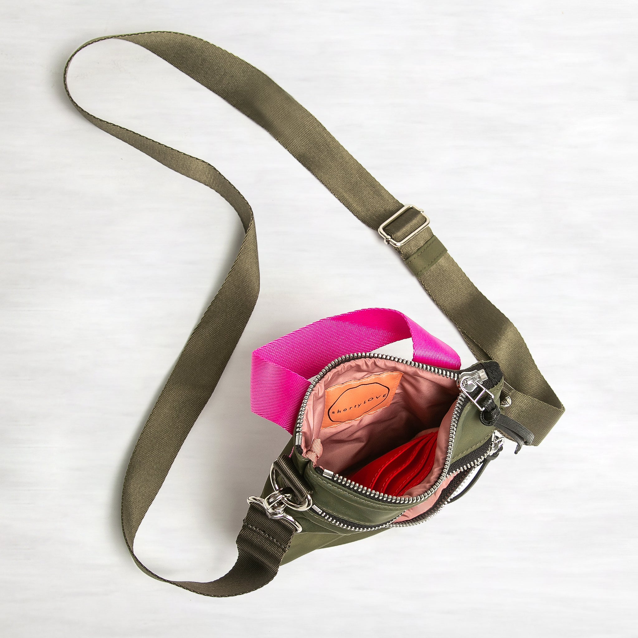 shortyLOVE shorthand crossbody phone bag in army green; top-down view showing interior pink lining against white background.