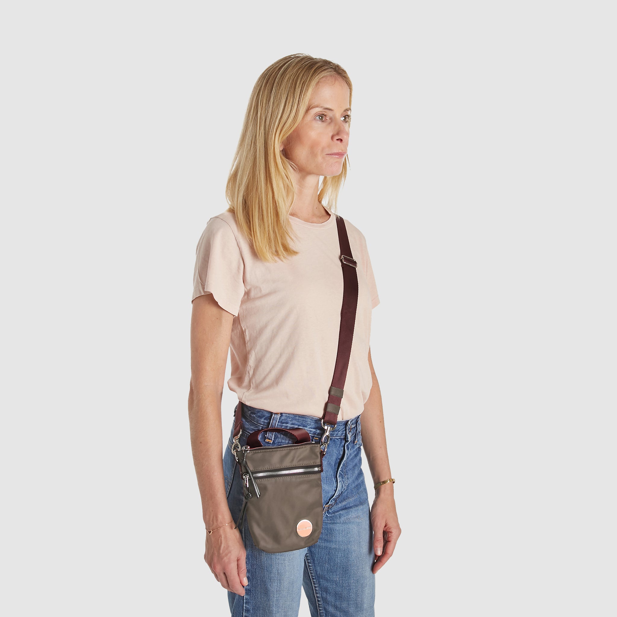 shortyLOVE shorthand small crossbody bag in mocha; on model in peach t-shirt and jeans against white background.