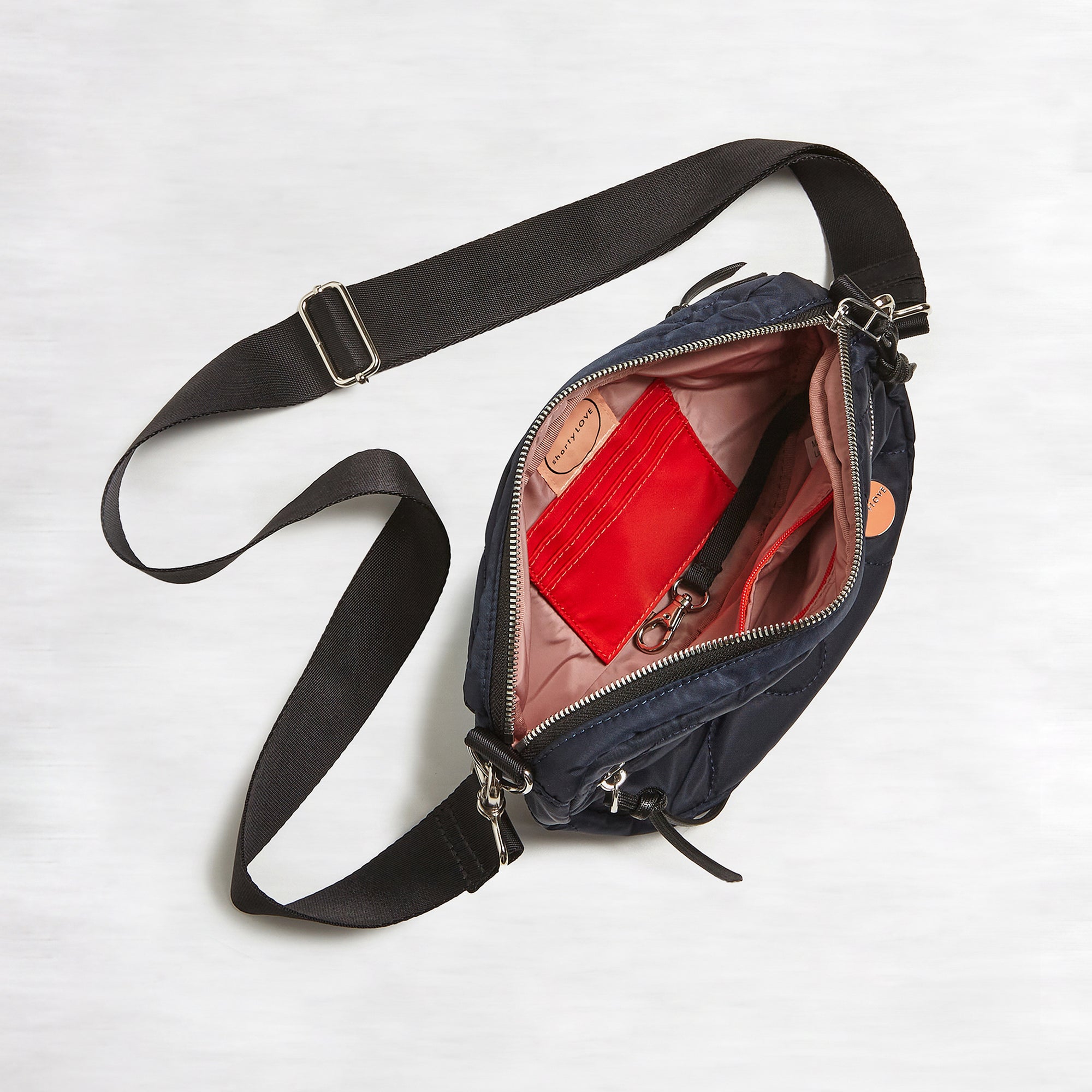shortyLOVE small cruiser small crossbody bag in midnight; top-down view showing interior blush lining against white background.
