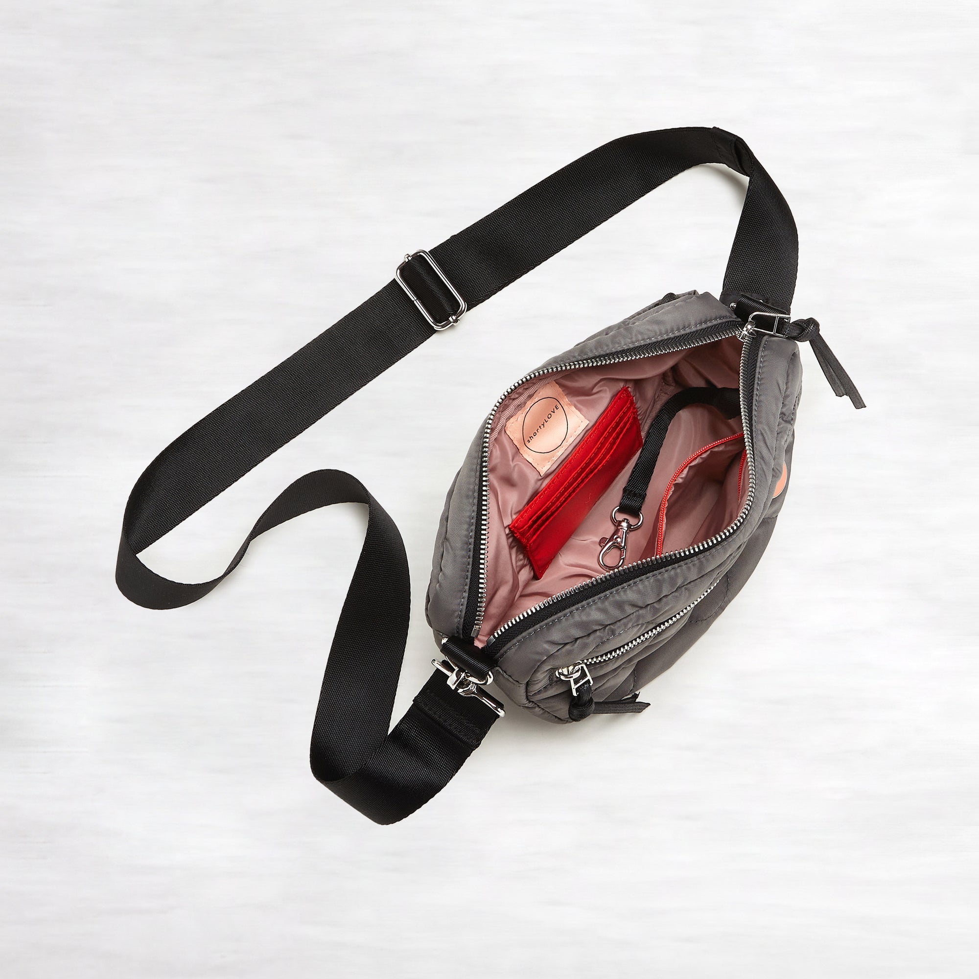 shortyLOVE small cruiser small crossbody bag in pewter; top-down view showing interior blush lining against white background.