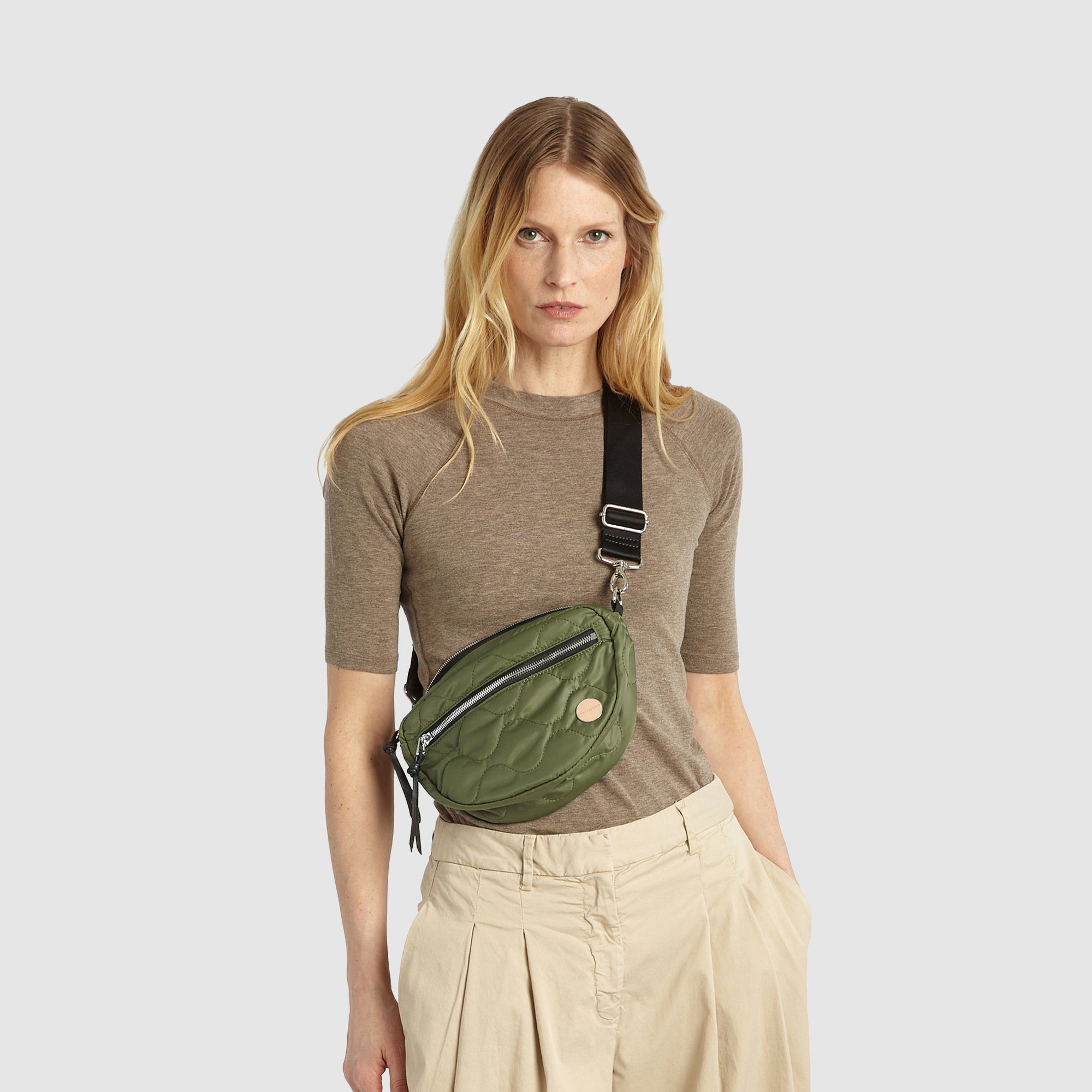 shortyLOVE small cruiser small crossbody bag in sage; on model in a tan top and pants against white background.