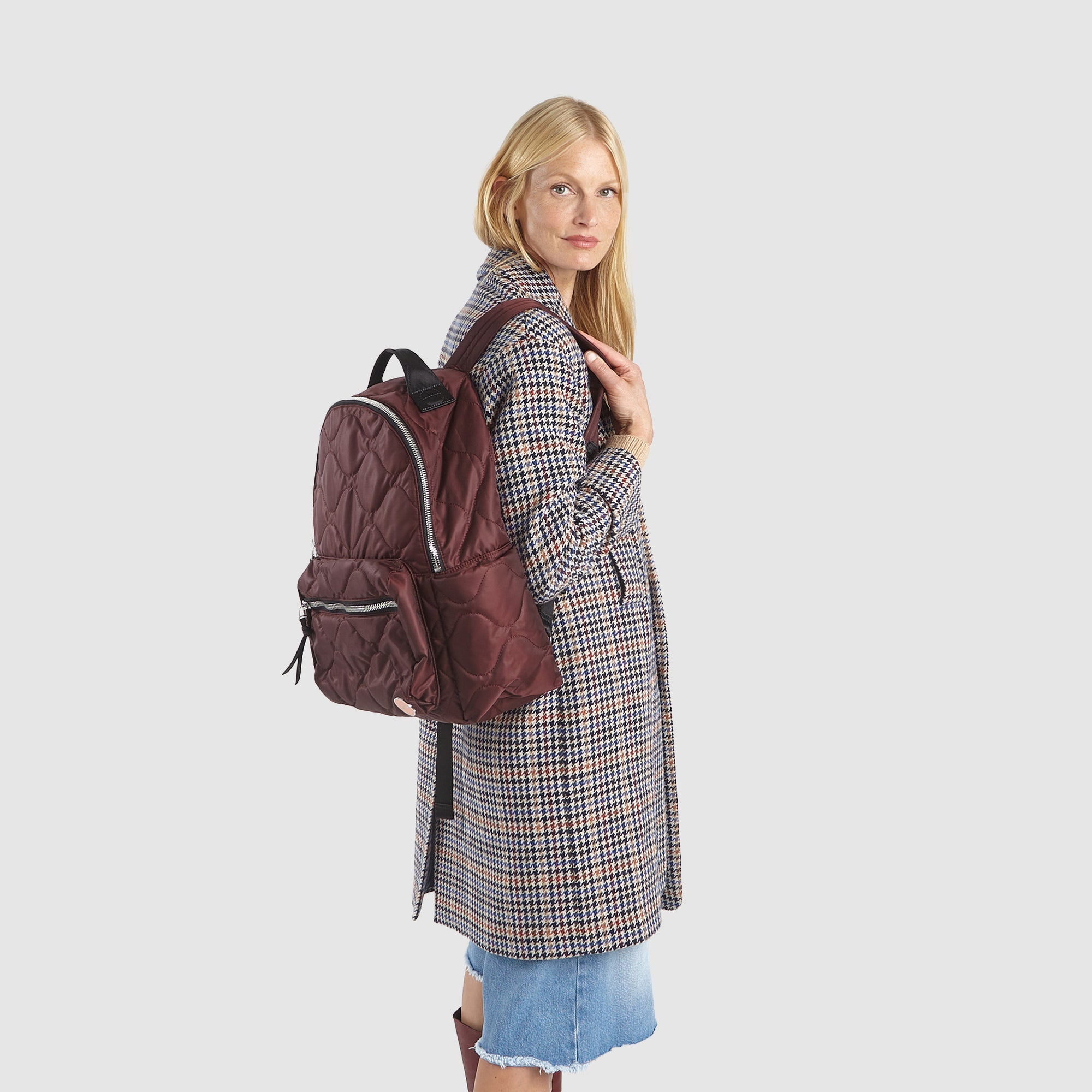 Model in coat wearing a shortyLOVE tate backpack in bordeaux