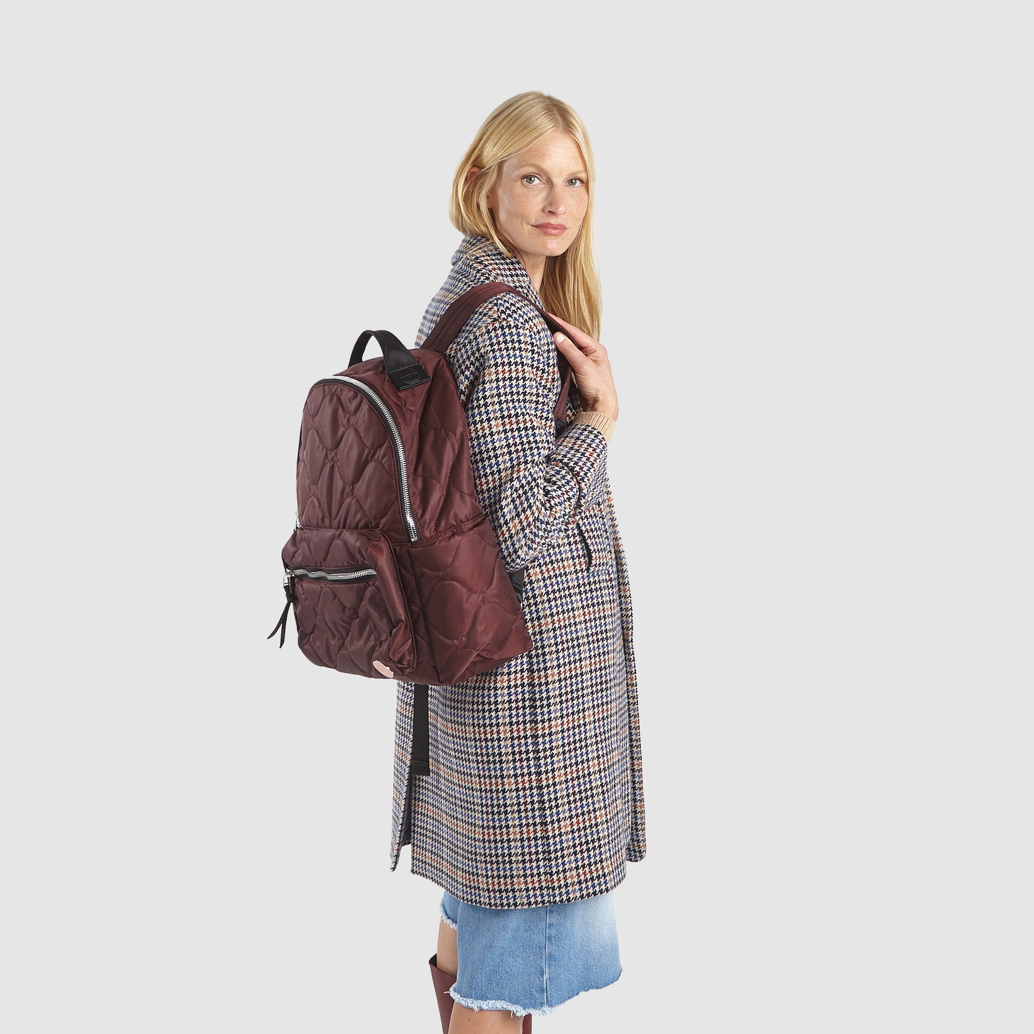 Model in coat wearing a shortyLOVE tate backpack in bordeaux