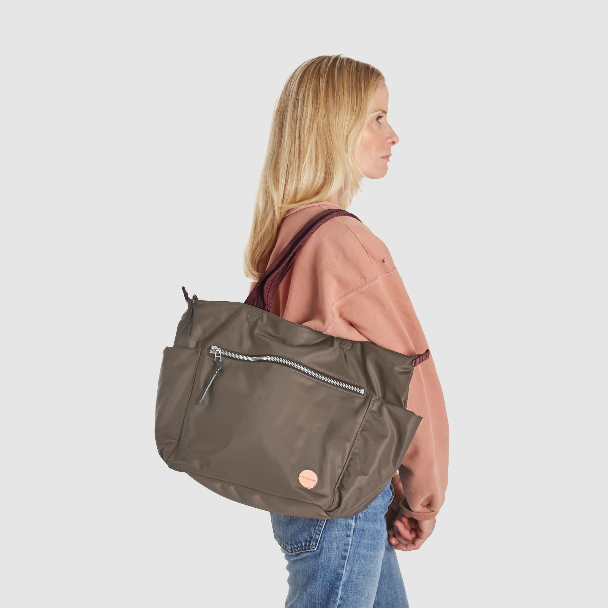 shortyLOVE tillie tote bag in mocha; on model in peach sweatshirt and jeans against white background.