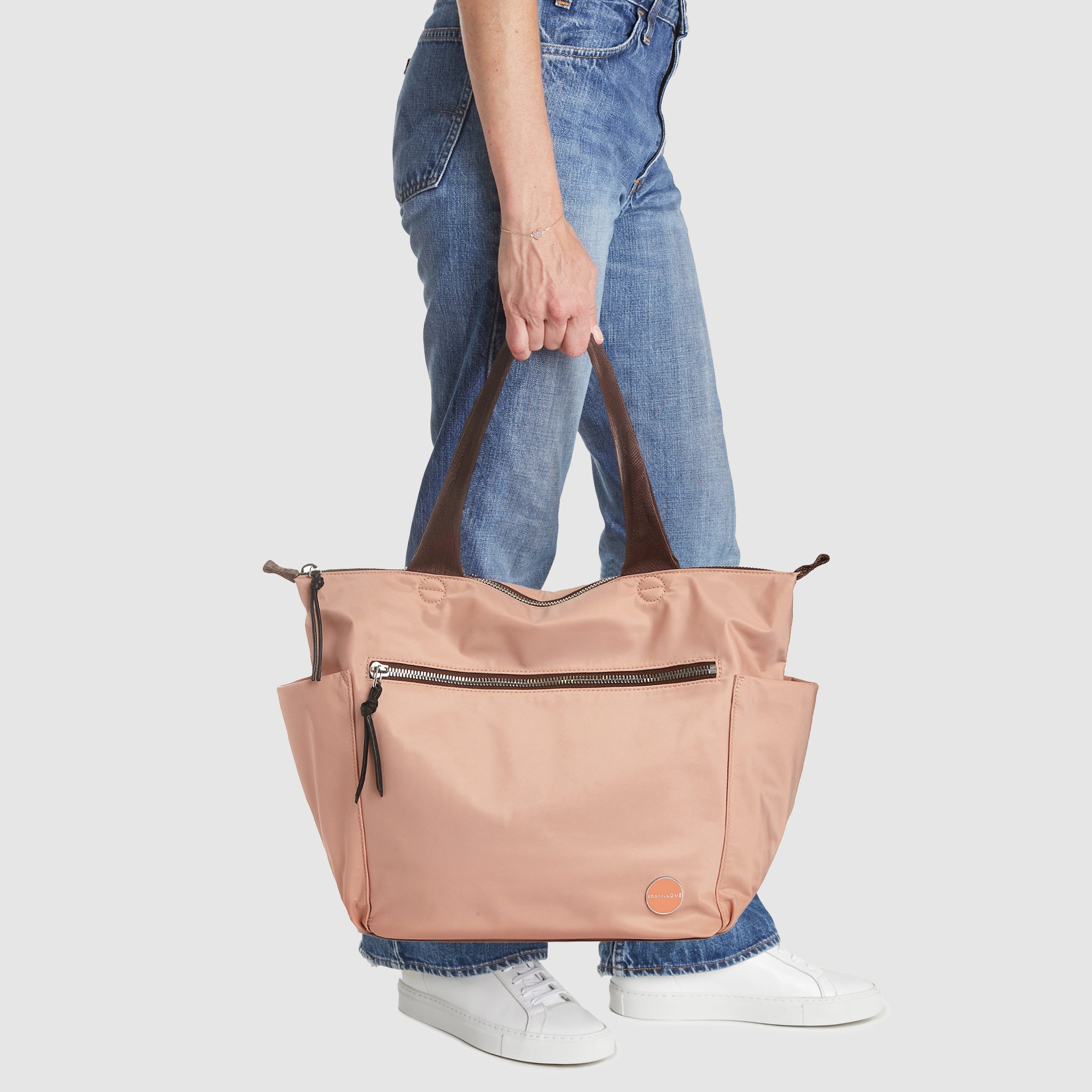 shortyLOVE tillie tote bag in dusty peach; in hand of model in  jeans against white background.