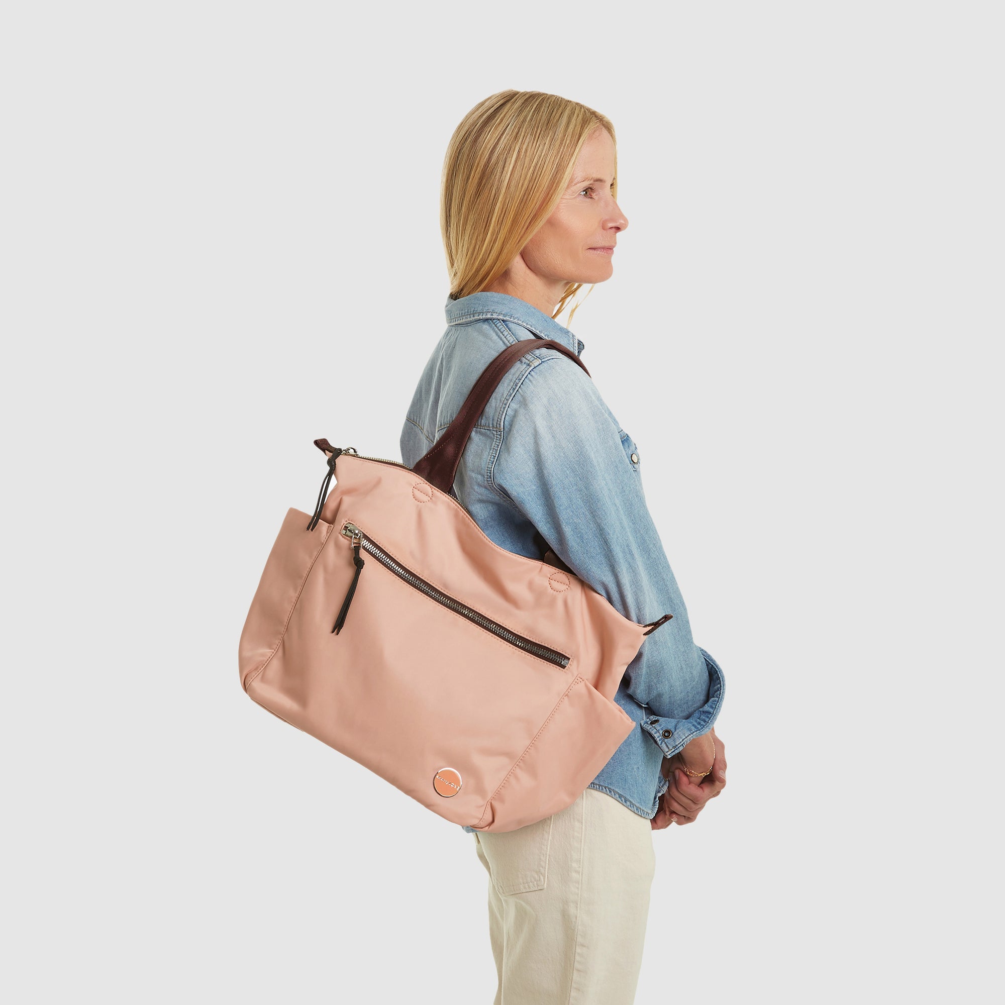 shortyLOVE tillie tote bag in dusty peach; on model in jean top and white jeans against white background.