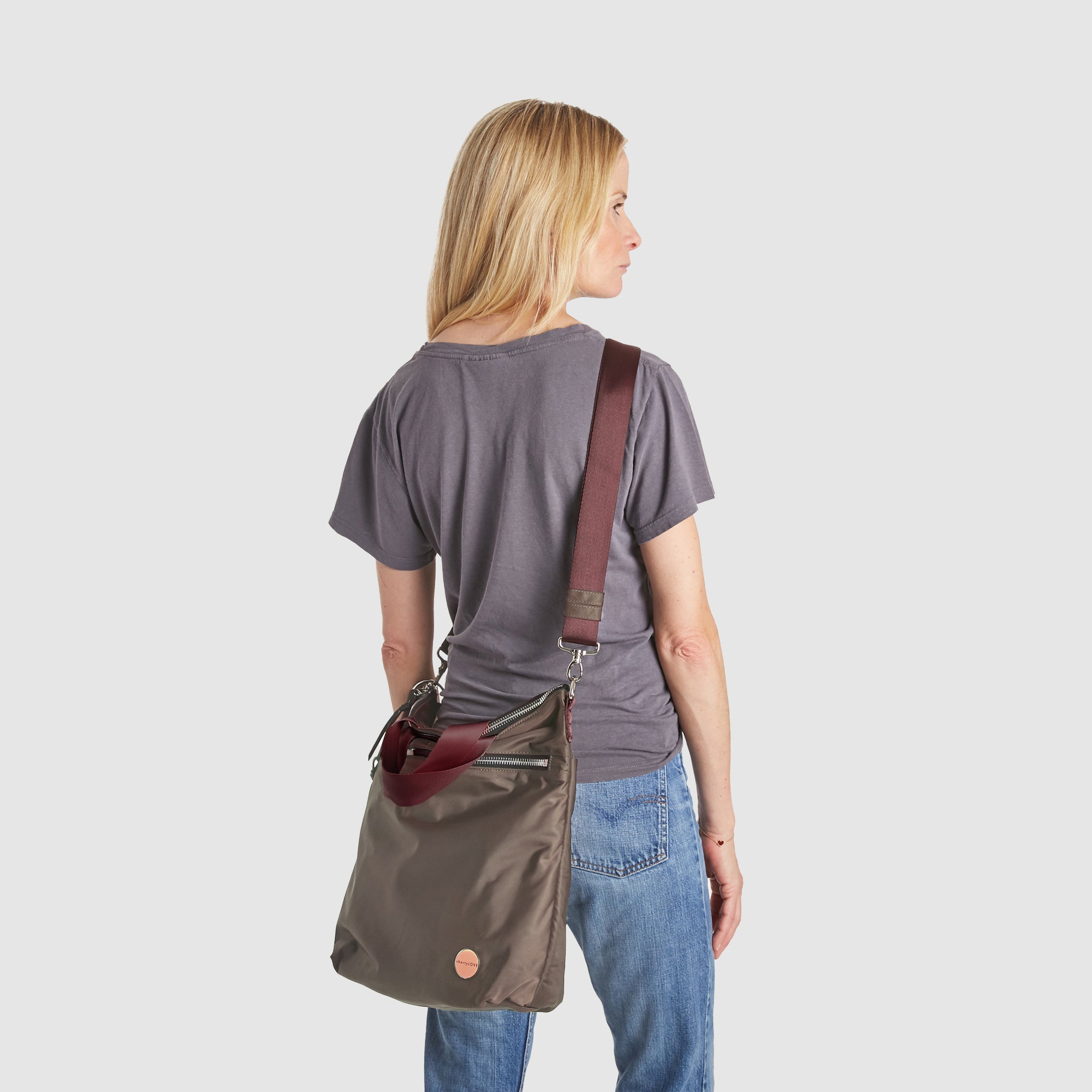 shortyLOVE wonder large crossbody/messenger bag in mocha; on model in grey t-shirt and jeans against white background.