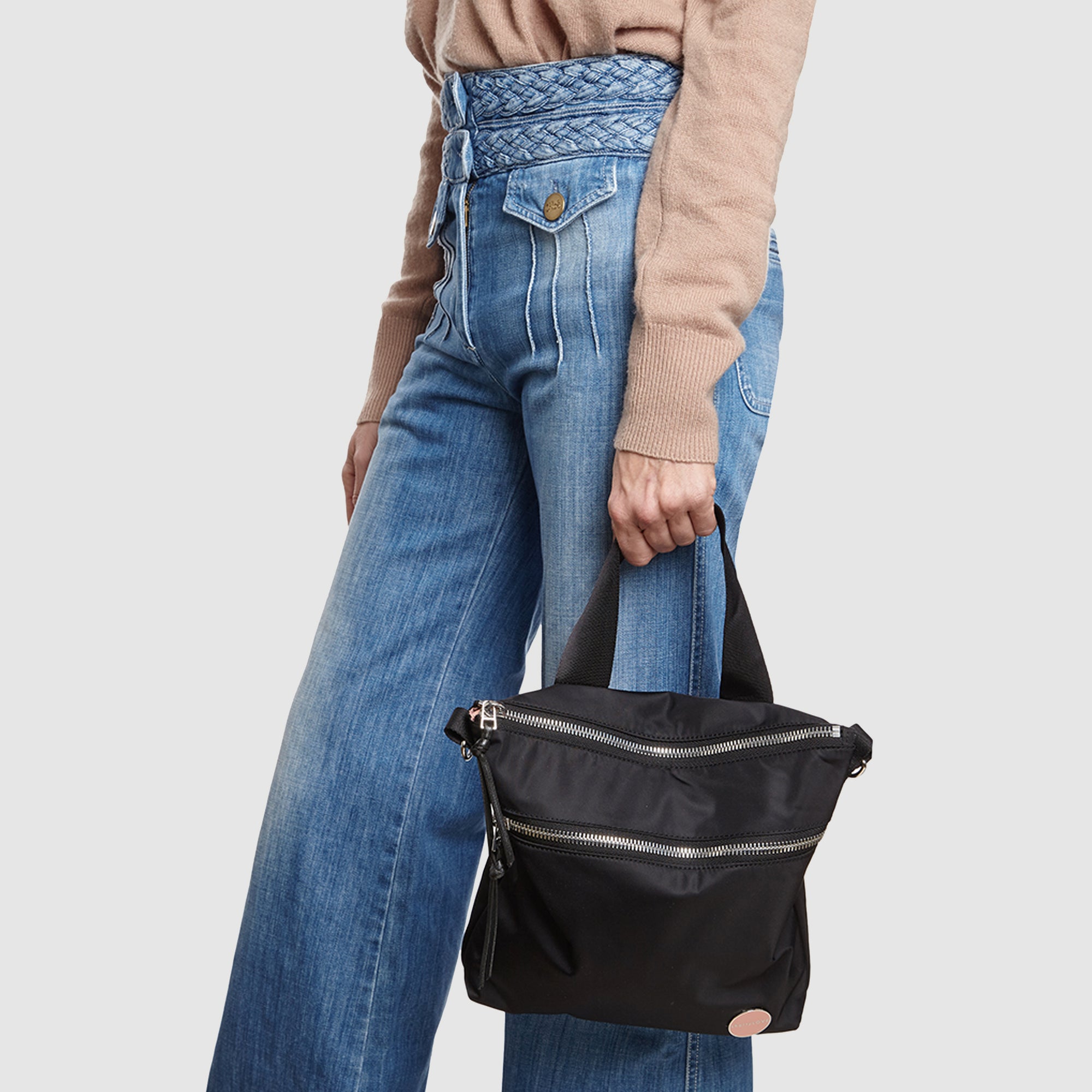 shortyLOVE amuse medium sized crossbody bag in black; on model in tan v-neck long sleeve sweater and jeans against white background.